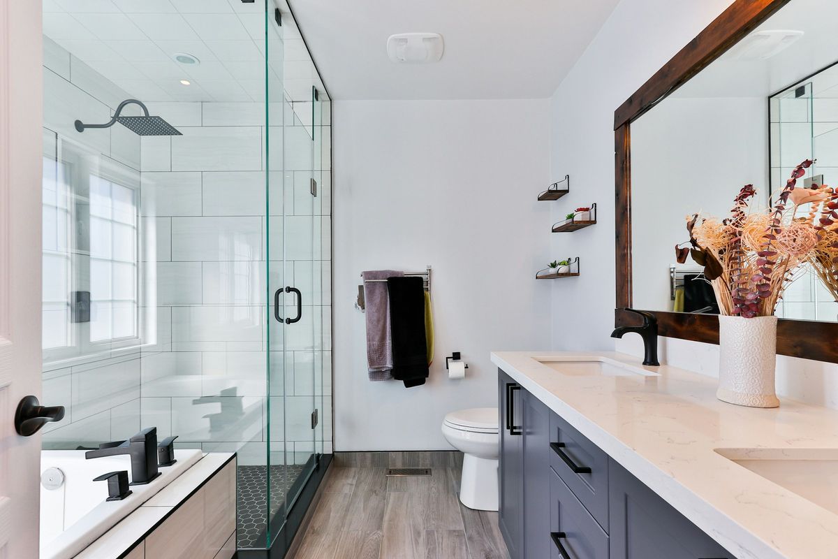Lichte badkamer met inloopdouche achter glas, dubbel lavabomeubel en houten vloer